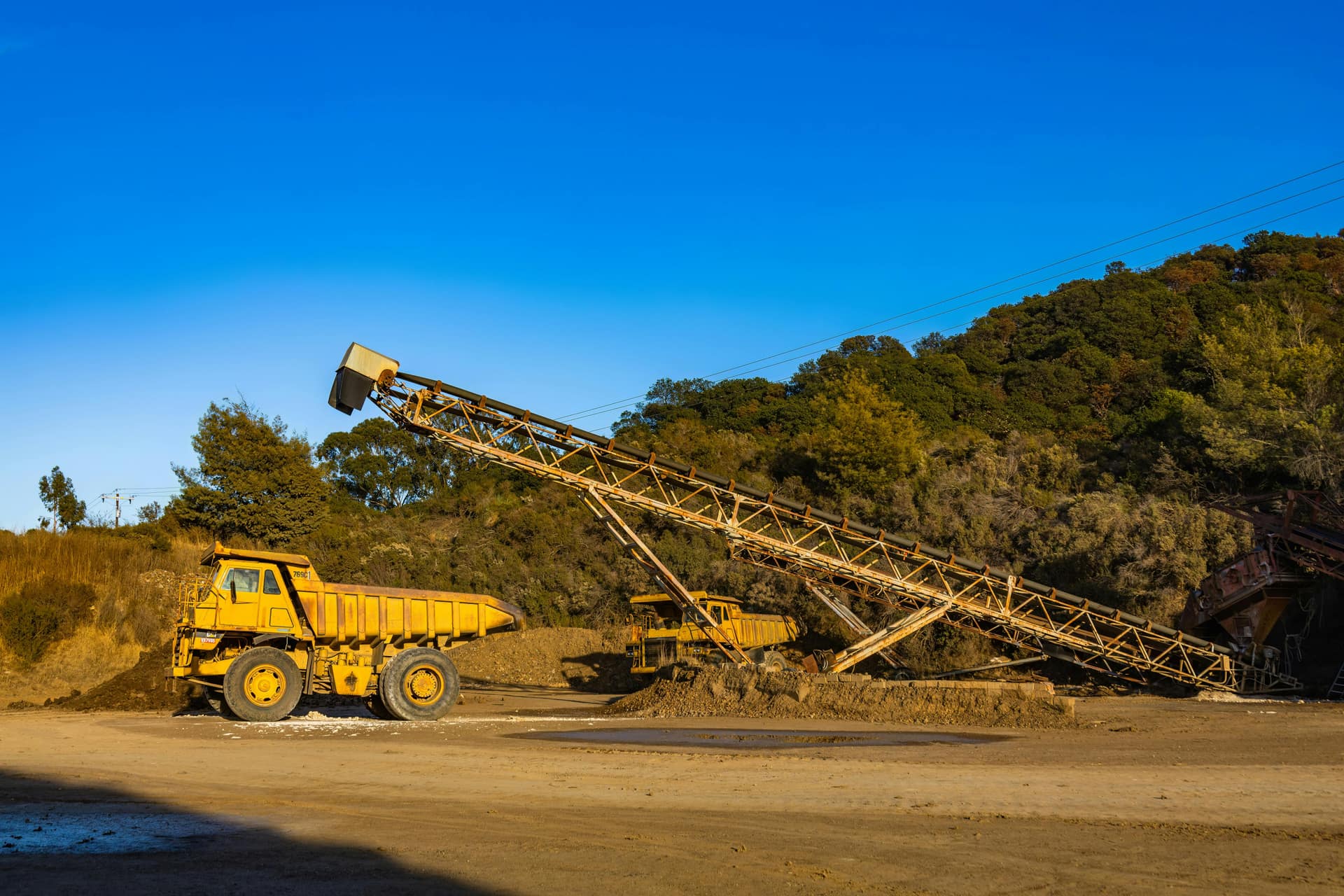 Haul trucks and a radial stacker building an ore stockpile